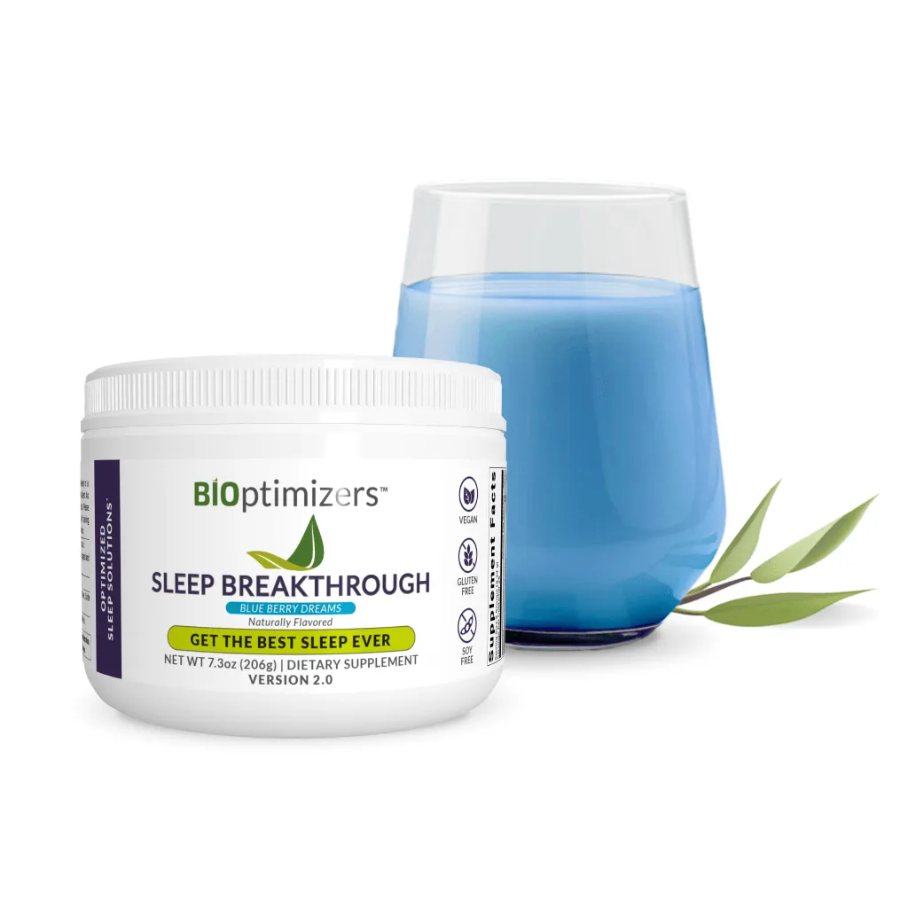 "A container of BiOptimizers Sleep Breakthrough dietary supplement in the Blueberry Dreams flavor, placed next to a glass filled with a blue liquid. The label highlights that the product is vegan, gluten-free, and soy-free. A small branch with green leaves is also included in the composition."